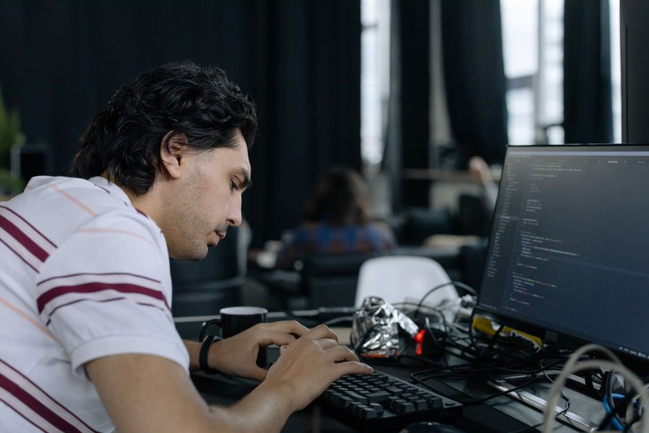 Programer intenzivno tipka na radnoj stanici u suvremenom uredskom okruženju